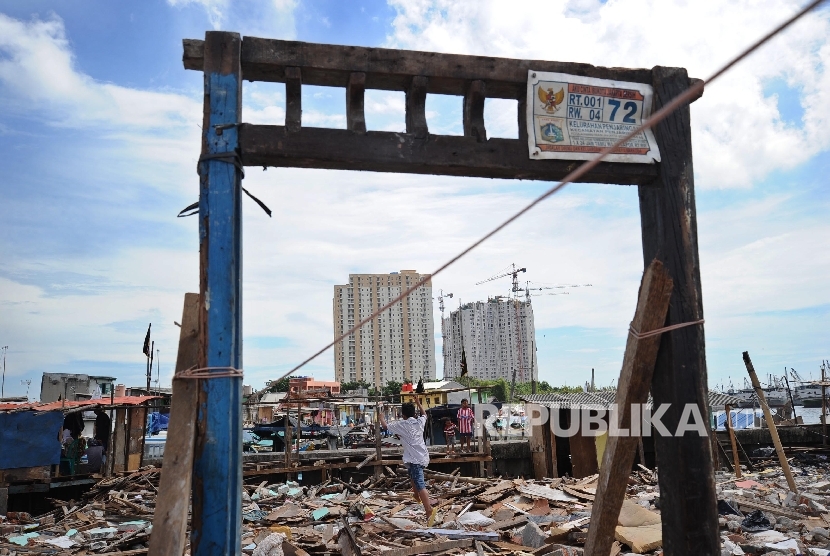  Warga melintas diantara puing sisa bangunan di kawasan Luar Batang, Penjaringan, Jakarta Utara , Selasa (5/3).(Republika/Tahta Aidilla)