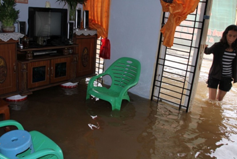 Warga melintas didepan rumahnya yang terendam banjir di Pekanbaru, Riau. Derasnya hujan yang mengguyur Pekanbaru sekitarnya, membuat Sungai Sail meluap yang mengakibatkan sedikitnya enam puluh rumah terendam banjir.
