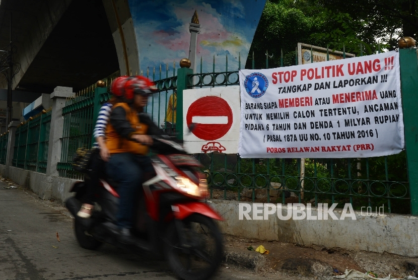  Warga melintas disamping spanduk berisikan seruan Stop Politik Uang yang terpasang di salah satu sudut Kota Jakarta Pusat, Ahad (15/1). 