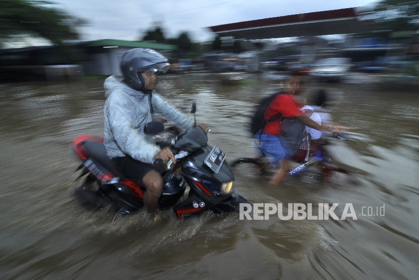 Warga melintas menggunakan motor saat banjir di Jalan Raya Baleendah, Kabupaten Bandung, Senin (3/10).