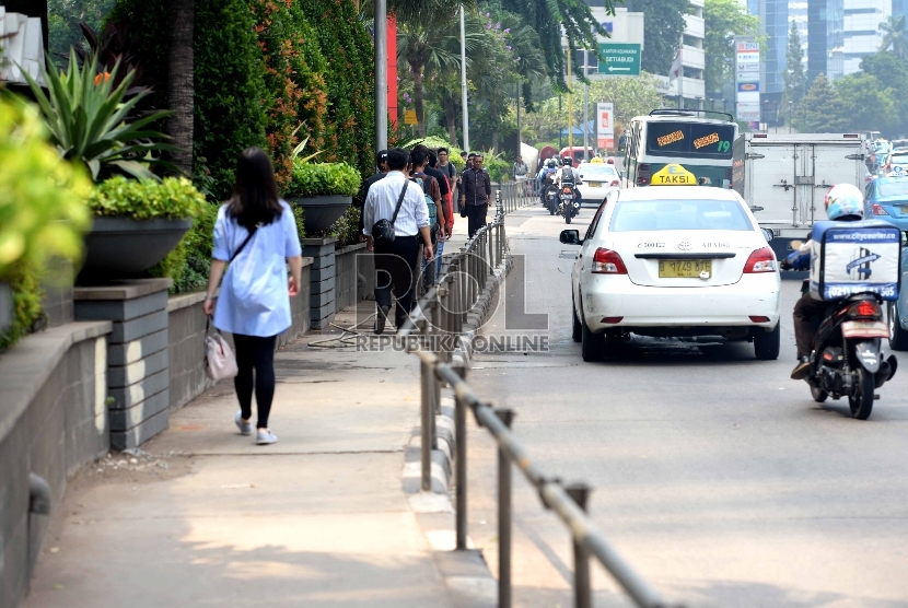  Warga melintas menggunakan trotoar di kawasan Jalan Sudirman, Jakarta Pusat, Jumat (20/11). 