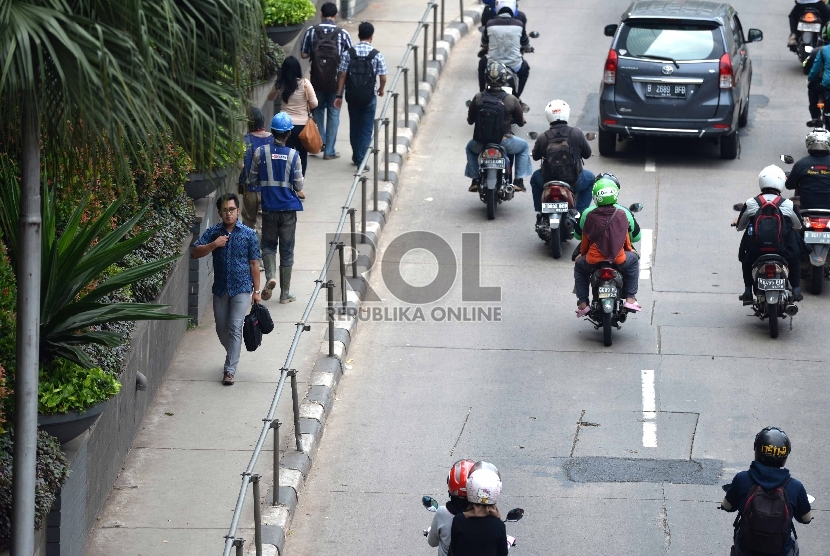 Warga melintas menggunakan trotoar di kawasan Jalan Sudirman, Jakarta Pusat, Jumat (20/11). 