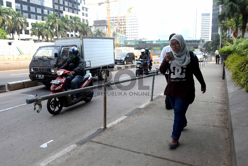 Warga melintas menggunakan trotoar di kawasan Jalan Sudirman, Jakarta Pusat, Jumat (20/11).