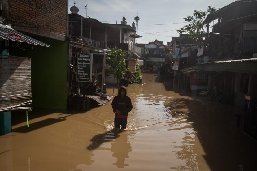 Warga melintasi air banjir yang menggenangi perkampungan di Pucang Sawit, Solo, Jawa Tengah, Sabtu (22/10/2022). Banjir tersebut disebabkan meluapnya air sungai Bengawan Solo karena hujan deras yang terjadi Jumat (21/10) sore hingga malam.