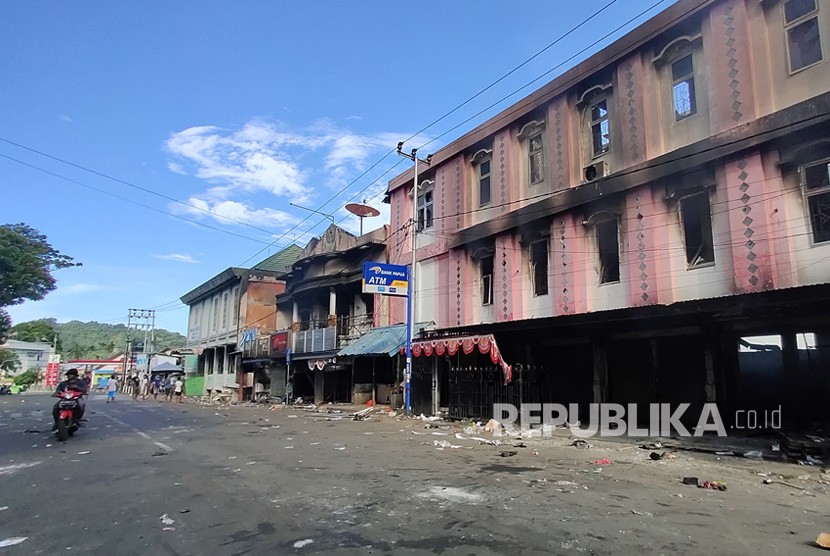 Warga melintasi bangunan yang rusak di Jayapura, Papua, Jumat (30/8/2019).