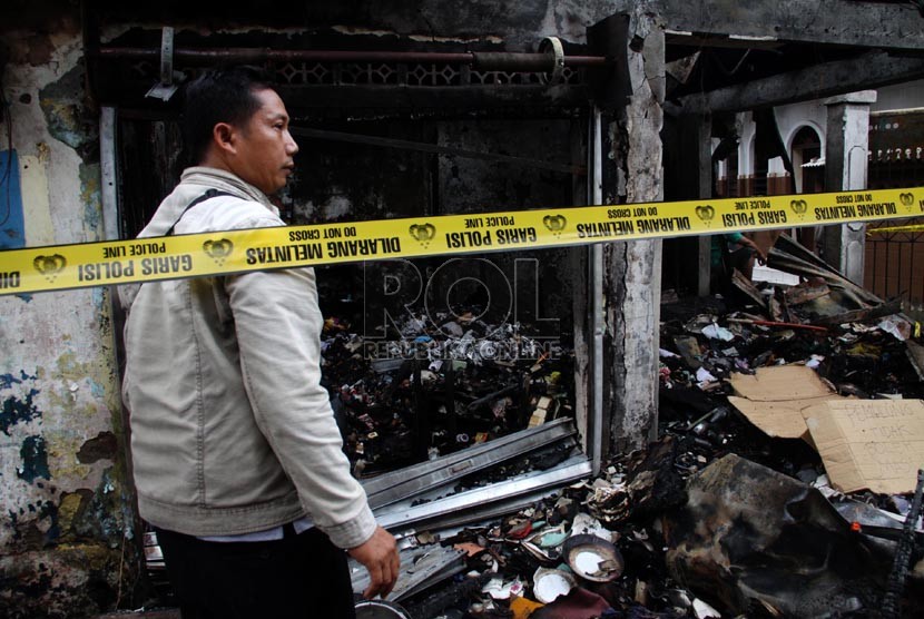   Warga melintasi bangunan yang terbakar akibat tawuran antarwarga di Johar Baru, Jakarta Pusat, Senin (18/11). (Republika/Yasin Habibi)