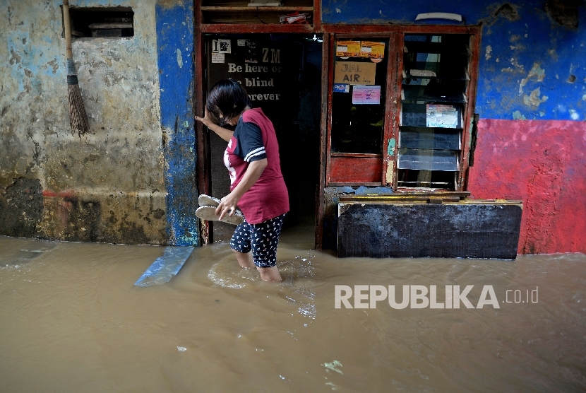  Warga melintasi banjir akibat luapan sungai Ciliwung di Kebon Pala II, Jakarta, Senin (13/2).