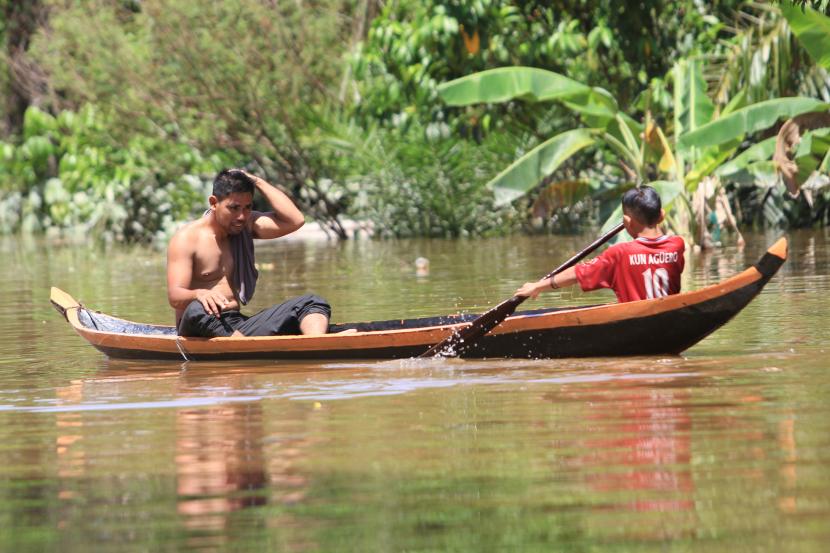 Warga melintasi banjir dengan menggunakan perahu (ilustrasi)
