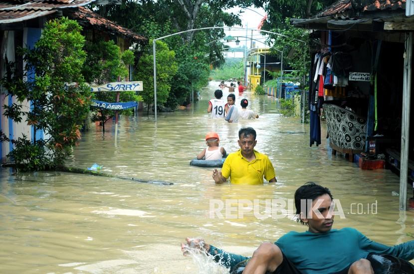 Warga melintasi banjir di wilayah Pamekasan, Jawa Timur. 