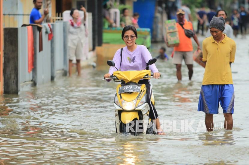 Warga melintasi banjir di Desa Widasari, Indramayu, Jawa Barat, Selasa (5/1/2021). Ratusan rumah di desa tersebut terendam banjir setingggi 50 cm hingga satu meter akibat luapan sungai Cibuaya.