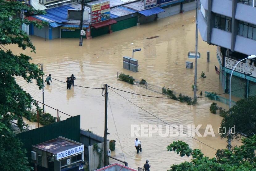 Warga melintasi banjir di Jalan Thamboosamy, Kuala Lumpur, Ahad (19/12). Sejumlah daerah di Lembah Klang, Malaysia, dilanda banjir yakni Kuala Lumpur, Selangor dan Putrajaya. 