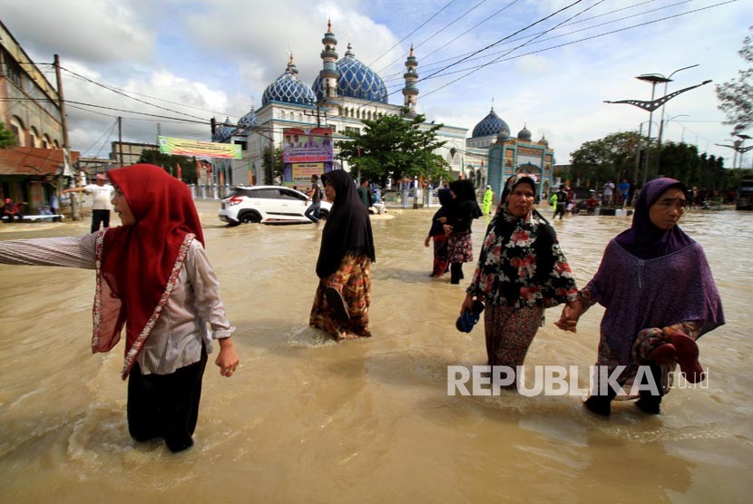 Warga melintasi banjir di Lhoksukon, Aceh Utara, Aceh, Senin (4/12)