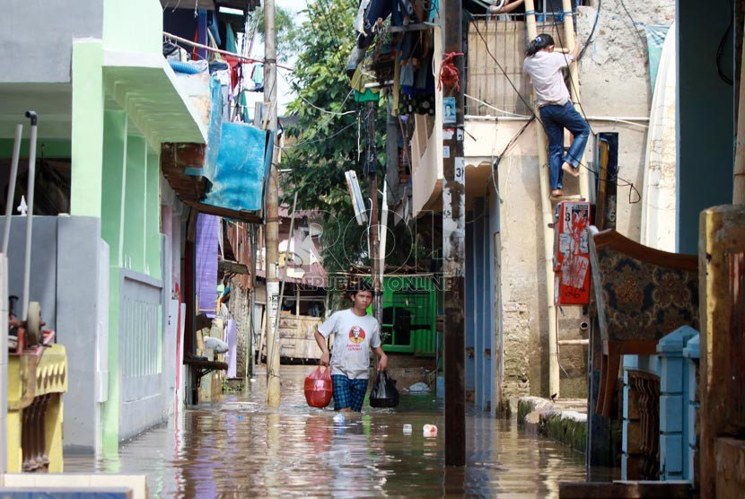 Warga melintasi banjir kiriman saat melanda kawasan Kampung Pulo, Jakarta Timur, Selasa (5/8). (Republika/ Yasin Habibi).