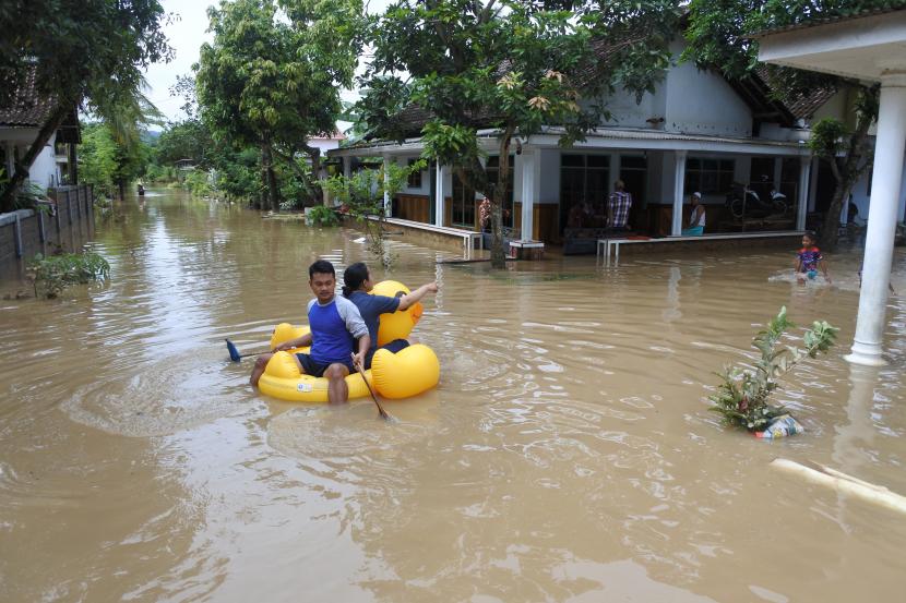 Warga melintasi banjir untuk mengungsi, di Balai Desa Wonoasri, Tempurejo, Jember, Jawa Timur, Jumat (15/1/2021). Sebanyak 2.558 KK di desa itu terdampak banjir dengan ketinggian air antara 50 Cm - 2 meter.
