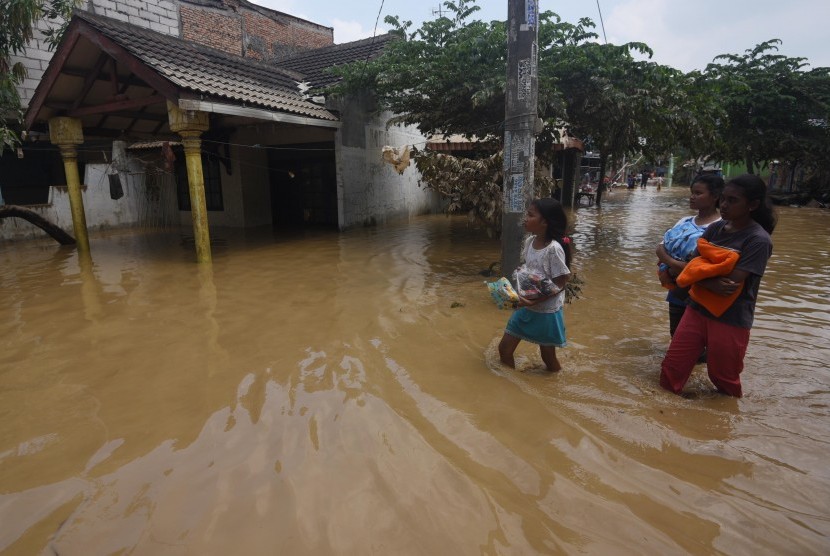 Warga melintasi banjir yang melanda kawasan Perumahan Pondok Gede Permai, Jatiasih, Bekasi, Jawa Barat, Jumat (22/4). (Antara/Akbar Nugroho Gumay)