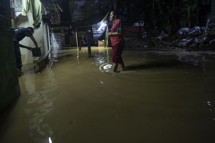 Warga melintasi banjir yang melanda lingkungan tempat tinggalnya di Pejaten Timur, Pasar Minggu, Jakarta, Ahad (7/2/2021). Banjir setinggi 30-150 cm yang melanda tiga RW di Pejaten Timur itu disebabkan oleh luapan air Sungai Ciliwung. 