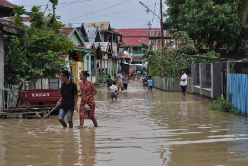 Warga melintasi banjir yang melanda permukiman warga di Kampung Baru, Palu, Sulawesi Tengah, Senin (29/4/2019). Banjir yang merendam puluhan rumah warga itu diakibatkan meluapnya air Sungai Palu akibat hujan lebat yang melanda wilayah hulu Sungai di Kabupaten Sigi. Kondisi itu dikhawatirkan akan semakin parah menyusul hujan deras yang masih terus terjadi dan mengakibatkan debit air Sungai Palu semakin meningkat. 