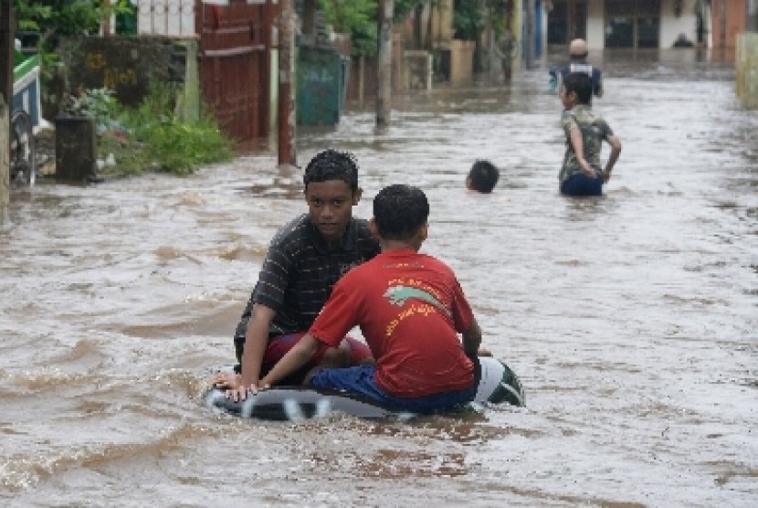 Warga melintasi banjir yang menggenangi kawasan Kampung Melayu, Jakarta, Senin (9/2).