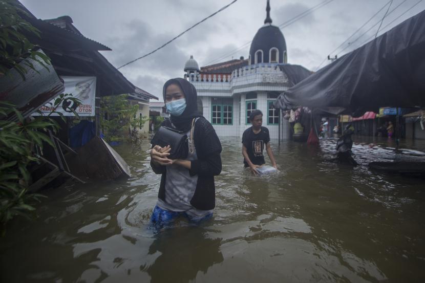 Warga melintasi banjir yang menggenangi kawasan padat penduduk di Kabupaten Banjar, Kalimantan Selatan.