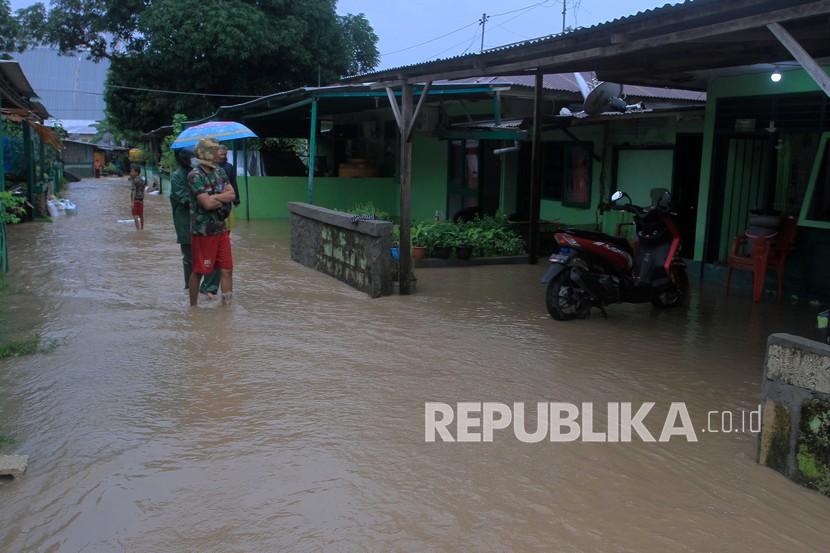 Warga melintasi banjir yang menggenangi permukiman di Kota Kupang, NTT, Rabu (23/2/2022). Hujan yang mengguyur wilayah tersebut sejak Selasa (22/2) hingga Rabu 23/2) tersebut mengakibatkan tanggul jebol dan sebanyak 84 rumah terendam banjir. 