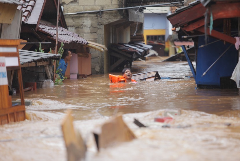 Warga melintasi banjir yang menggenangi Perumahan kawasan Jalan H. Ipin, Pondok Labu, Jakarta, Rabu (1/1). BMKG menyebut hujan intensitas tinggi di awal 2020 karena pengaruh perubahan iklim 