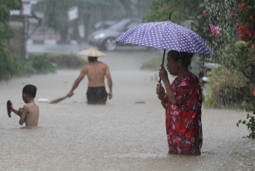 Warga melintasi banjir yang merendam wilayah permukimannya. (ilustrasi)