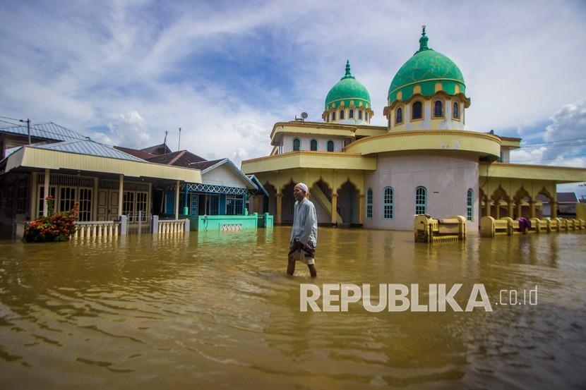 Warga melintasi banjir yang merendam permukiman di Desa Dalam Pagar Ulu, Kabupaten Banjar, Kalimantan Selatan, Ahad (19/12/2021). Banjir yang disebabkan meluapnya sungai Martapura dan sungai Kiwa itu merendam sejumlah desa di enam Kecamatan di Kabupaten Banjar. 