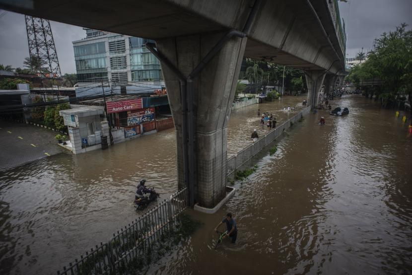 Warga melintasi berjalan banjir di Jalan Kapten Tendean, Mampang Prapatan, Jakarta, Sabtu (20/2/2021). Banjir tersebut disebabkan karena curah hujan tinggi sejak Jumat (19/2) malam.