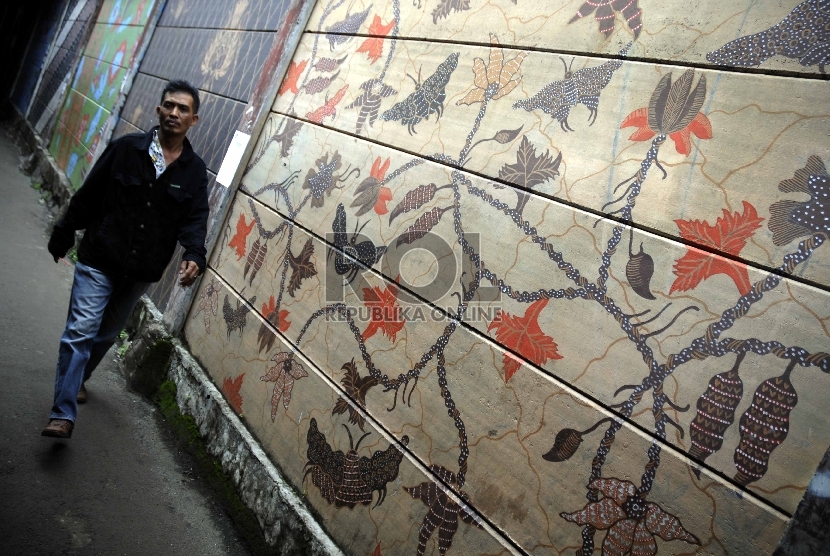 Warga melintasi dinding yang dihiasi mural bermotif batik di kawasan padat penduduk,Kecamatan Menteng, Jakarta Pusat, Jumat (6/2). (Republika/Rakhmawaty La'lang)