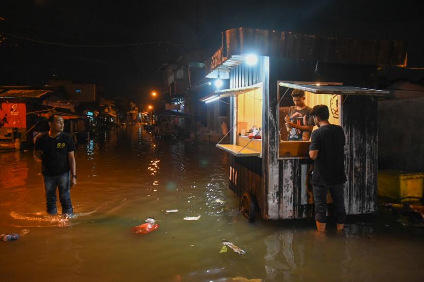 Warga melintasi genangan air akibat banjir rob di kawasan Bagan Deli, Belawan, Medan, Sumatera Utara. Walkot Medan Bobby Nasution sebut pembangunan tembok rob Belawan dilakukan tahun ini.