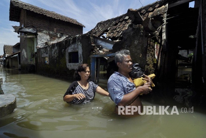 Warga melintasi genangan air di Desa Cigosol, Kecamatan Baleendah, Kabupaten Bandung, Jumat (3/3)