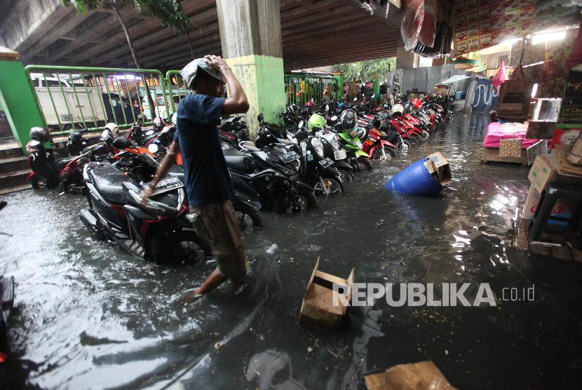 Warga melintasi genangan air di Pasar Blok G Tanah Abang, Jakarta, Senin (11/12). Hujan dengan intensitas tinggi disertai derainase saluran air yang buruk sehingga menyebabkan tergenangnya air di pasar tesebut. 