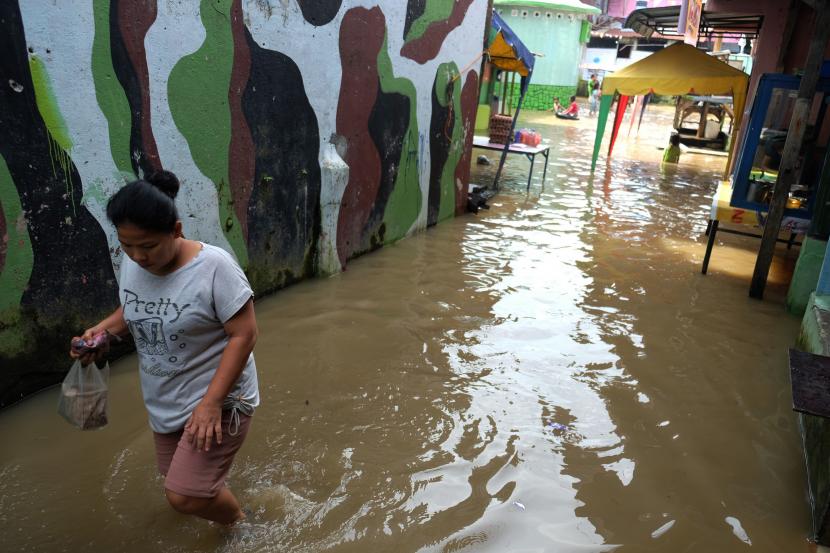 Warga melintasi genangan air yang merendam permukiman penduduk akibat meluapnya aliran Sungai Deli, di Kelurahan Aur, Medan, Sumatera Utara, Jumat (11/9/2020). Puluhan rumah di daerah tersebut terendam banjir akibat meluapnya Sungai Deli.