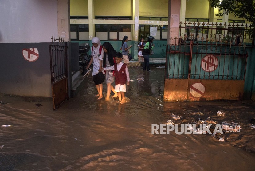 Warga melintasi genangan banjir bandang di SDN 224, Sukup Baru, Ujungberung, Bandung, Jawa Barat, Senin (1/4/2019).