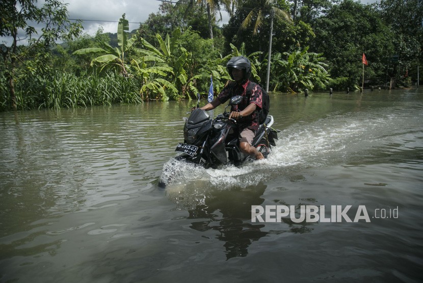 Warga melintasi genangan banjir di jalan Parangtritis, Donotirto, Kretek, Bantul, DI Yogyakarta, Senin (18/3/2019).