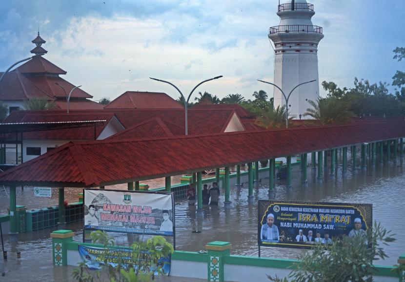 Warga melintasi genangan banjir di kawasan Mesjid Agung Kesultanan Banten, Kasemen, Kota Serang, Selasa (1/3/2022). Banjir di 22 titik yang terdapat di 4 kecamatan tersebut terjadi setelah hujan lebat sejak Senin (28/2) dan dilaporkan sebanyak dua orang meninggal dunia, ratusan warga mengungsi serta puluhan rumah rusak.
