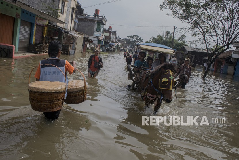 Warga melintasi genangan banjir luapan sungai Citarum di Kawasan Baleendah, Kabupaten Bandung, Jawa Barat, Jumat (5/4/2019).