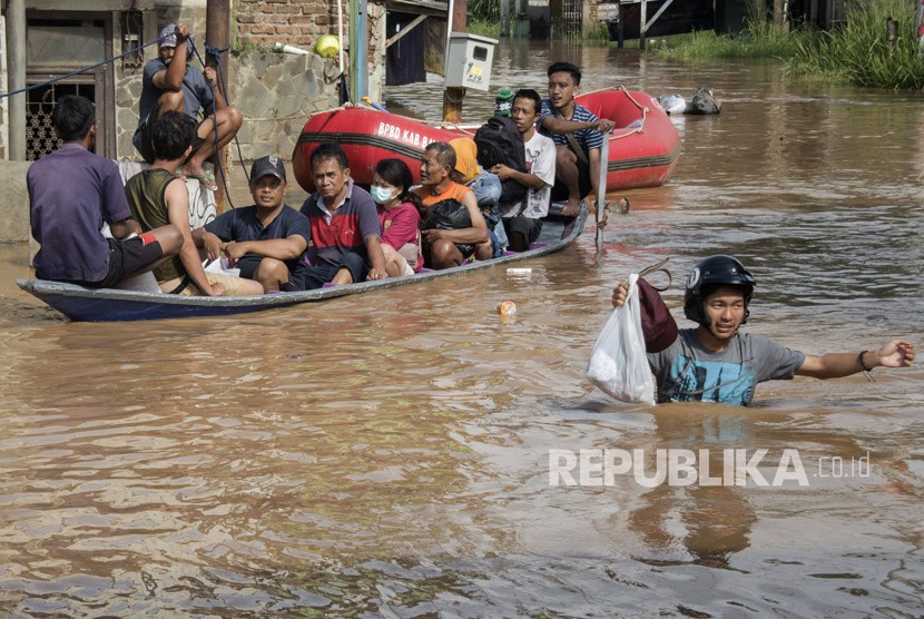 Warga melintasi genangan banjir untuk berevakuasi di Dayeuhkolot, Kabupaten Bandung, Jawa Barat, Jumat (23/2).