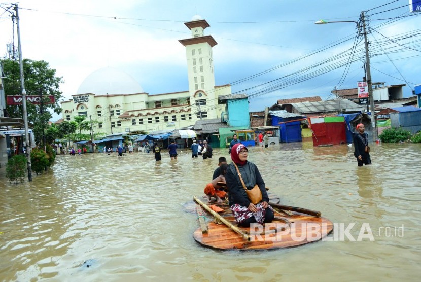 Warga melintasi Jalan Raya Dayeuhkolot, Kabupaten Bandung yang sudah tergenang banjir akibat luapan Sungai Citarum, Kamis (9/3).