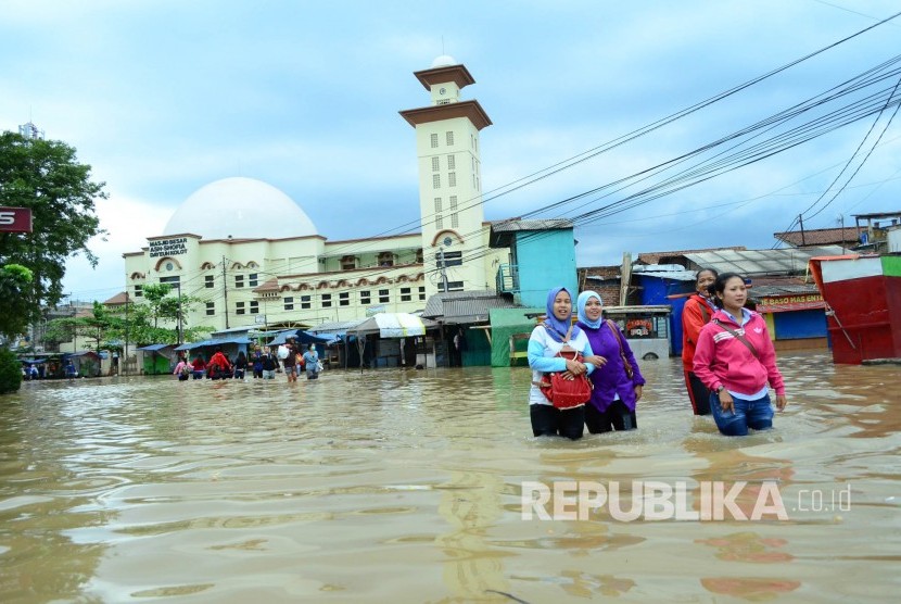 Warga melintasi Jalan Raya Dayeuhkolot, Kabupaten Bandung yang sudah tergenang banjir akibat luapan Sungai Citarum, Kamis (9/3).