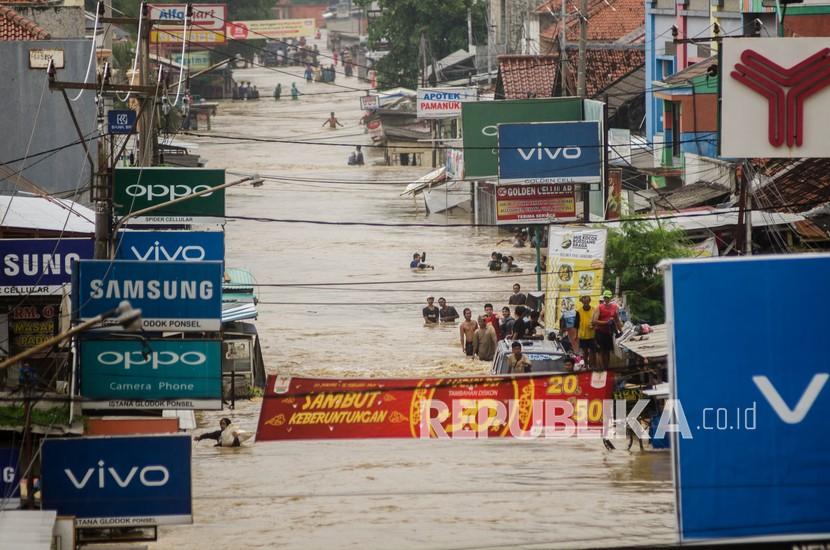 Warga melintasi jalan raya yang terendam banjir di Pamanukan, Kabupaten Subang, Jawa Barat karena meluapnya Sungai Cipunagara. PUPR mengeklaim Bendungan Sadawarna bisa mengendalikan debit Sungai Cipunagara.