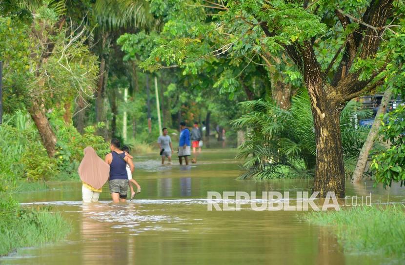 Warga melintasi jalan yang masih terendam banjir, di Padang, Sumatera Barat (ilustrasi)