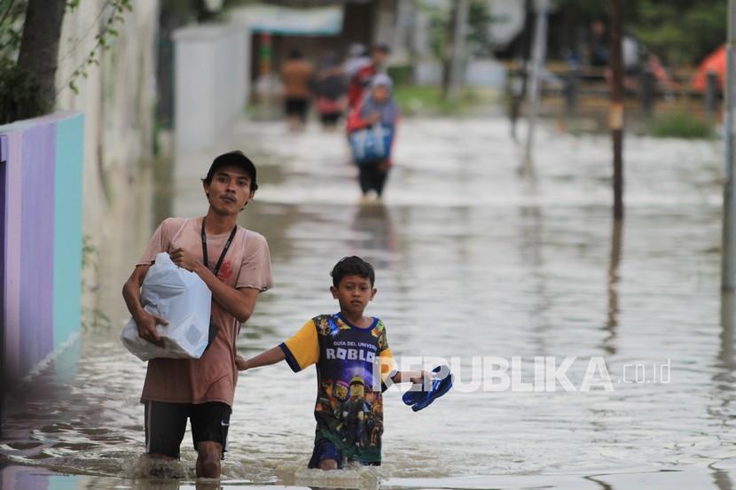 Warga melintasi jalan yang terendam banjir di desa Babadan, Kecamatan Sindang, Indramayu, Jawa Barat, Senin (8/2/2021). BPBD Kabupaten Indramayu mencatat sedikitnya 21 kecamatan di Indramayu terdampak banjir akibat luapan air dari sejumlah sungai yang berada di DAS Cimanuk-Cisanggarung dan DAS Citarum. 