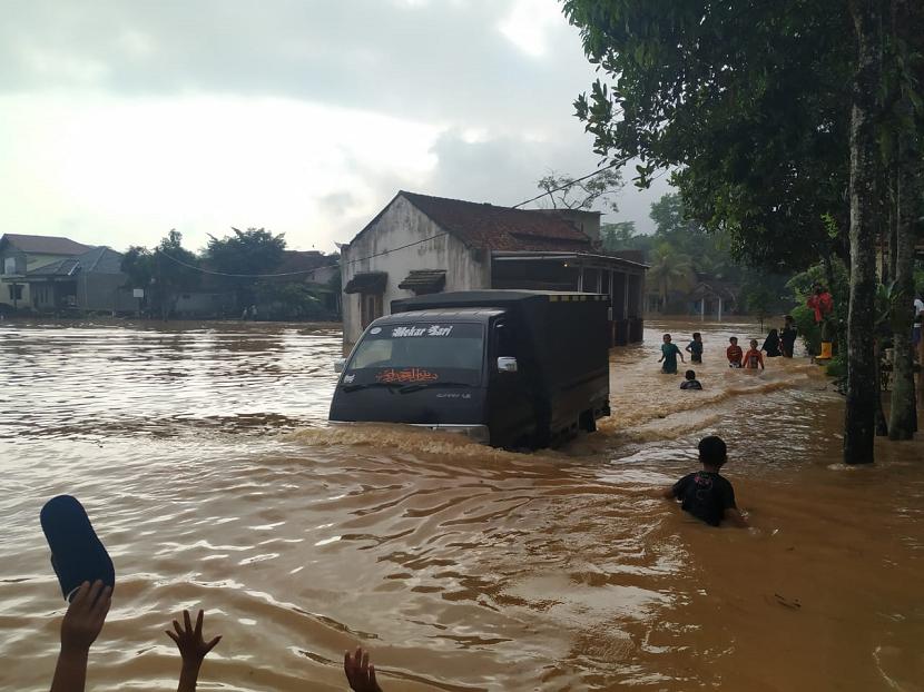 Warga melintasi jalan yang terendam banjir di Desa Tanjungsari, Kecamatan Sukaresik, Kabupaten Tasikmalaya, Rabu (10/6).