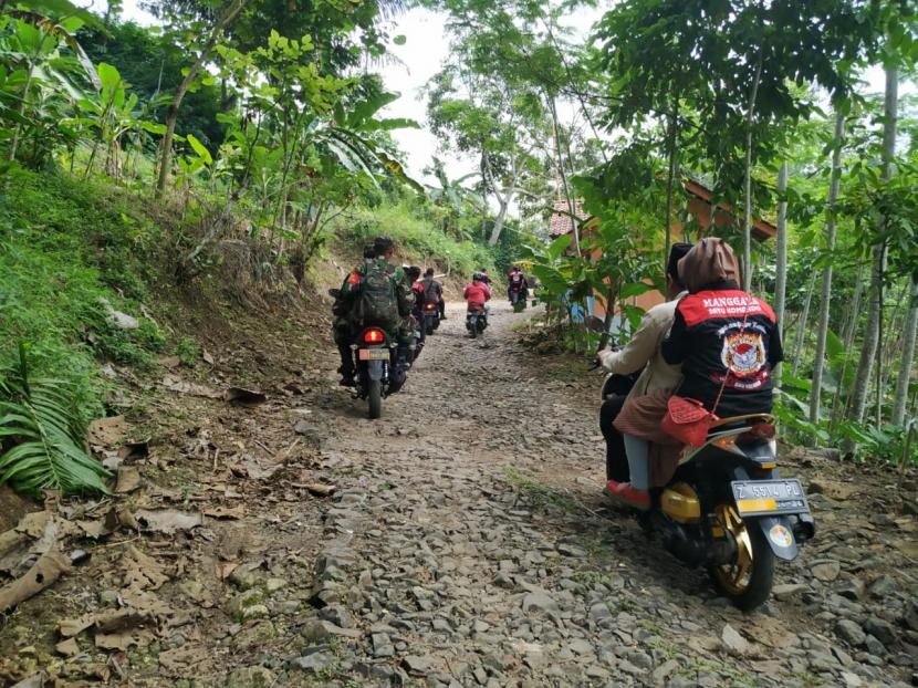 Warga melintasi jalanan yang rusak di Desa Cikubang, Kecamatan Taraju, Kabupaten Tasikmalaya, Jumat (26/6). 