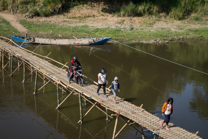Warga melintasi jembatan bambu di atas Sungai Bengawan Solo yang menghubungkan Desa Mojolaban, Sukoharjo dengan Kampung Sewu di Solo, Jawa Tengah, Rabu (19/6/2019).
