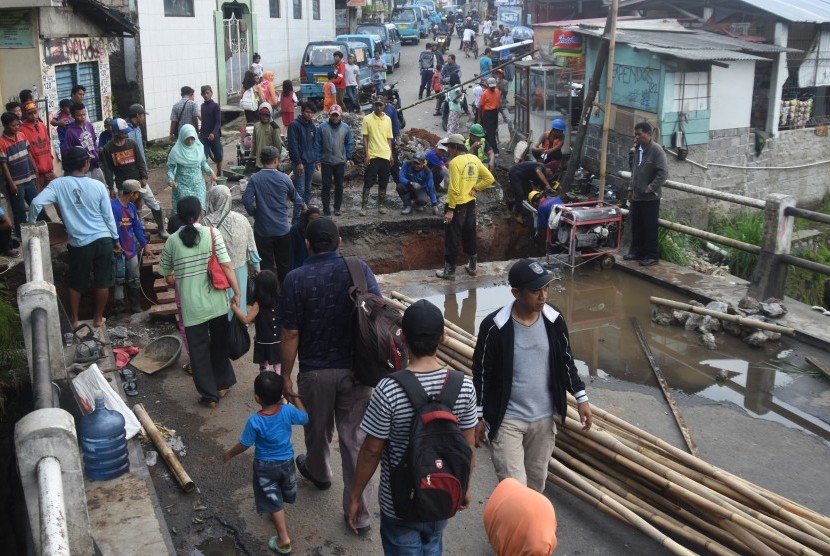 Warga melintasi jembatan darurat akibat amblasnya Jembatan Kali Krukut di Jalan Pitara, Depok, Jawa Barat, Rabu (3/5).