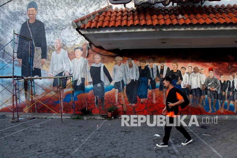 Warga melintasi mural bergambar sejumlah pemimpin negara-negara anggota Forum G20 berbusana adat Suku Badui di Pasar Nongko, Solo, Jawa Tengah, beberapa waktu lalu.