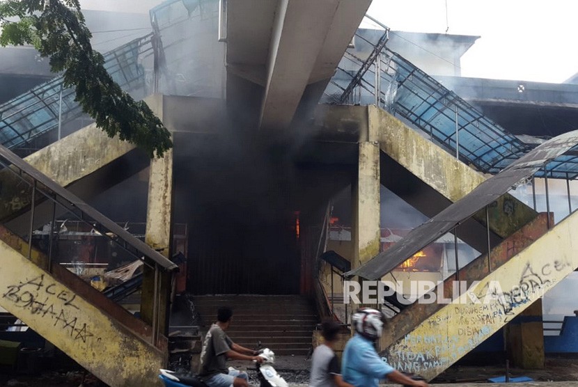 Warga melintasi Pasar Tambruni yang dibakar massa saat melakukan aksi di Kabupaten Fak-Fak, Papua Barat, Rabu (21/8/2019). 