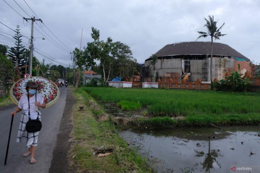 Warga melintasi pembangunan fasilitas gedung untuk perhelatan World Water Forum (WWF) ke-10 di kawasan Museum Subak, Desa Banjar Anyar, Tabanan, Bali, Senin (22/4/2024). 